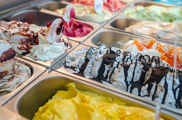 Different flavors of ice-crem displayed in containers in dessert shop