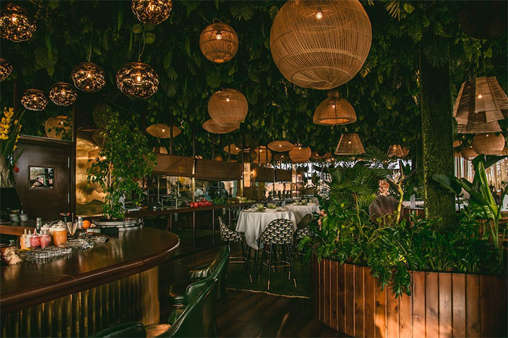 Layered intimate lighting in lush restaurant interior