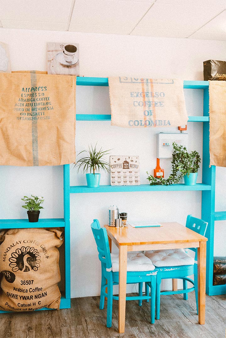Quaint cafe corner with turquoise furniture and hardwood floors.
