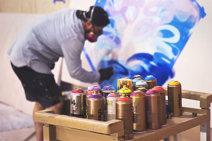 Artist at work in front of a large wall. 