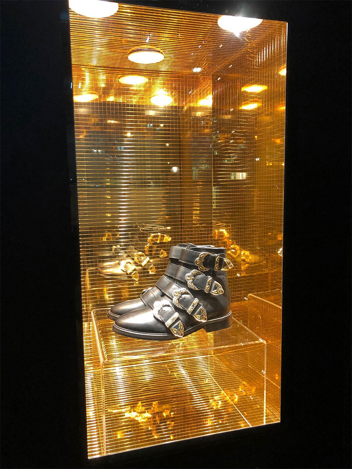 Gold disco-vibe decorative panels as a background for shoes in a display window.