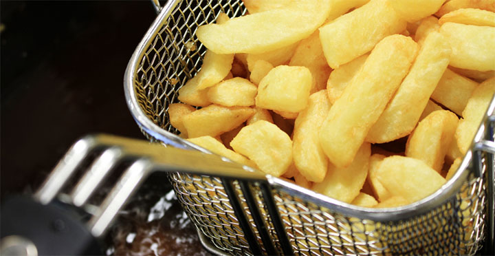 Deep fryer basket full of French fries.