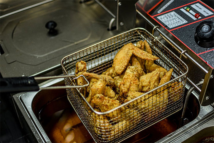 Chicken wings being cooked in a fryer.