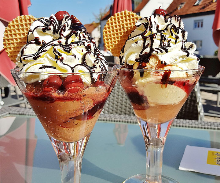 Delicious desserts in tall glasses, topped with whipped cream and a cherry.