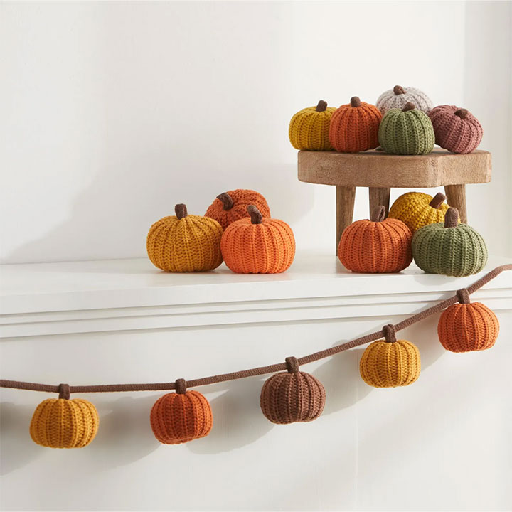 Knit pumpking garland on a mantel.