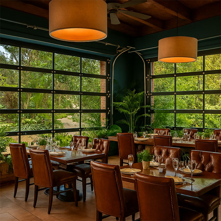 Restaurant with upholstered chairs surrounded by gourgeous garden.